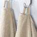 Two IKEA VITBACKEN beige bath towels hanging on hooks, one using its loop for easy hanging