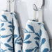 IKEA VITBACKEN blue and white leaf pattern cotton towels hanging on hooks, one folded