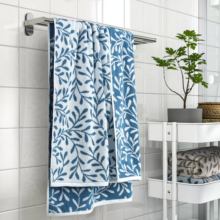 IKEA VITBACKEN blue leaf pattern bath towel hanging on rail beside bathroom shelf with plant