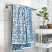 IKEA VITBACKEN blue leaf pattern bath towel hanging on rail beside bathroom shelf with plant