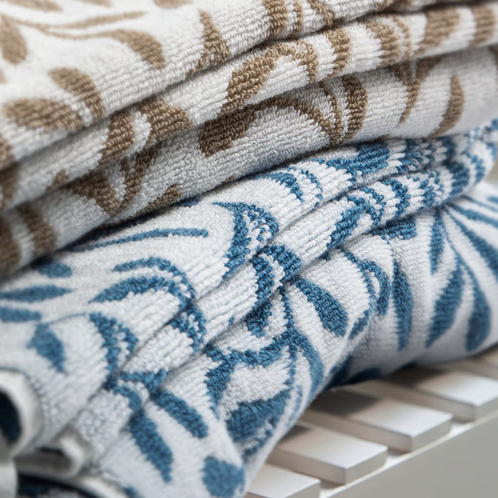 Stacked IKEA VITBACKEN cotton terry towels in blue and white leaf patterns