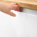  Person opening IKEA VOXTORP matt white kitchen cabinet door demonstrating integrated handle grip