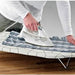 Person ironing clothes on the IKEA Ironing Board Table, showing ample surface area and sturdy construction 40242889