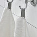 A close-up image of a folded White hand towel with a textured pattern 30512886