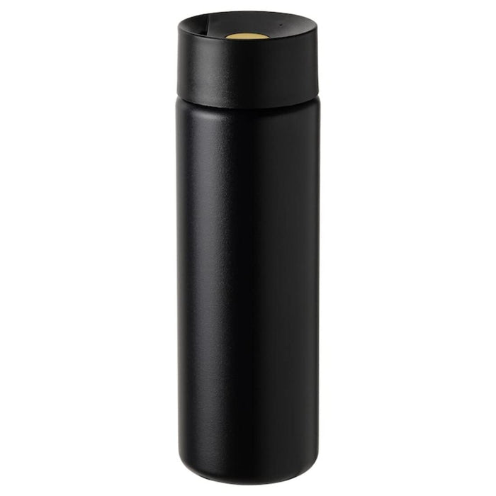 A vacuum flask with a double-walled construction, filled with hot tea and placed on a wooden table. 50497272