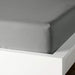 A closeup image of IKEA fitted sheet on a bed with neatly tucked corners and a smooth surface