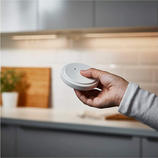 A person holding the IKEA ANSLUTA Remote Control in their hand, demonstrating its size and ease of use. 20314274 
