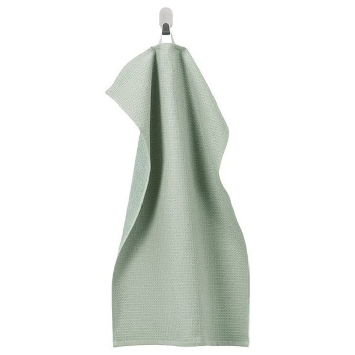 A hand towel from the Ikea 6 Piece Combo Set in light green, hanging from a towel hook on a beige bathroom wall.