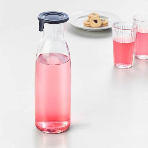 Digital Shoppy Ikea carafe with lid , A close-up image of an IKEA carafe with a clear glass body and a lid made of cork. The carafe is filled with lemonade and placed on a white tablecloth. 302.919.22