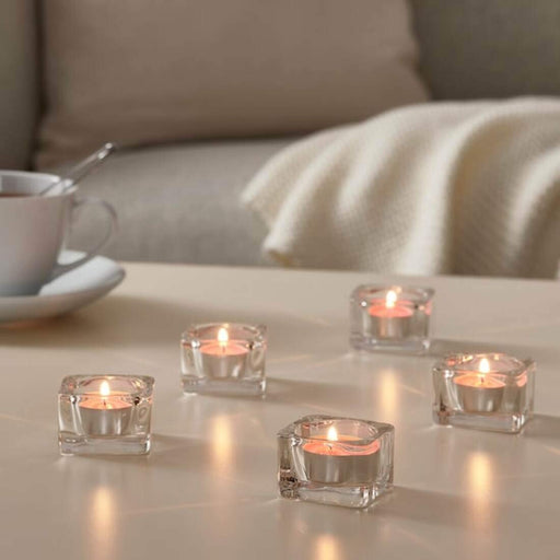 IKEA scented tealight candle burning on a wooden surface, with soft light and subtle fragrance filling the room.