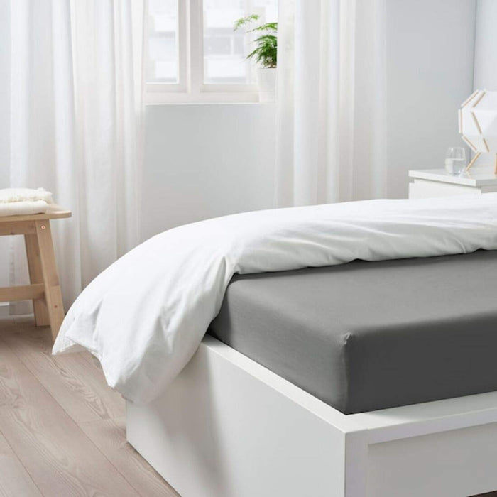 A grey IKEA fitted sheet on a bed with neatly tucked corners and a smooth surface- 30482460