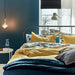 A cozy-looking bed with a colorful duvet cover and matching pillowcases from IKEA  80431581
