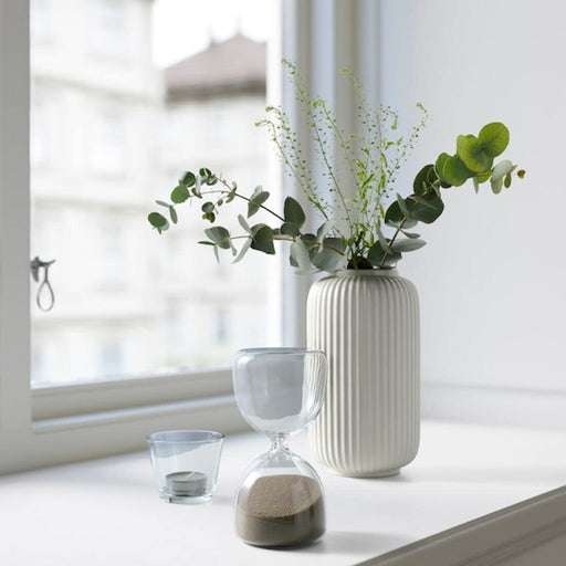 Hourglass on wooden table with sand flowing through - perfect decorative piece for home.