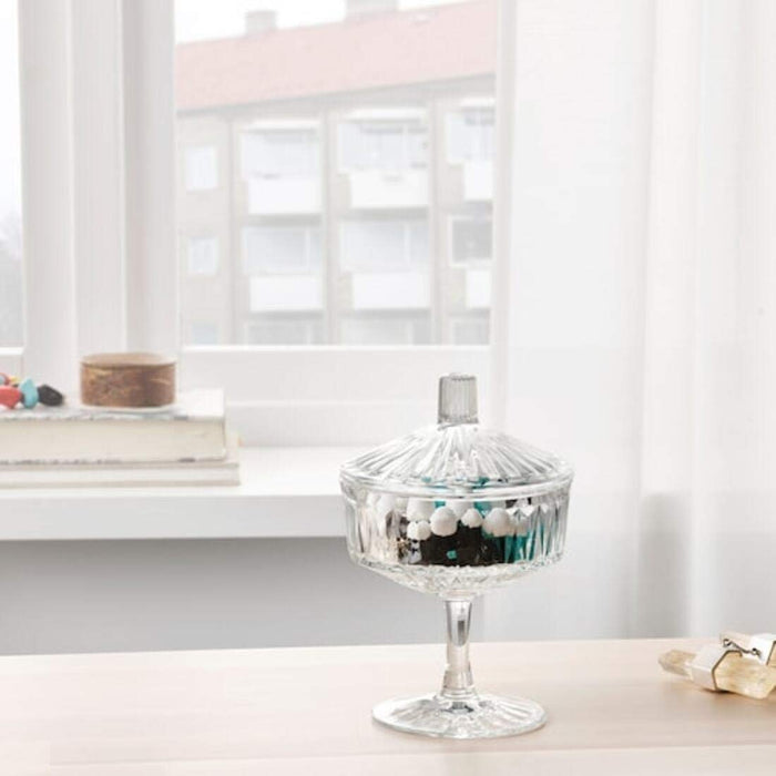 A functional and elegant clear glass bowl with lid from IKEA, ideal for storing small items and keeping them fresh.