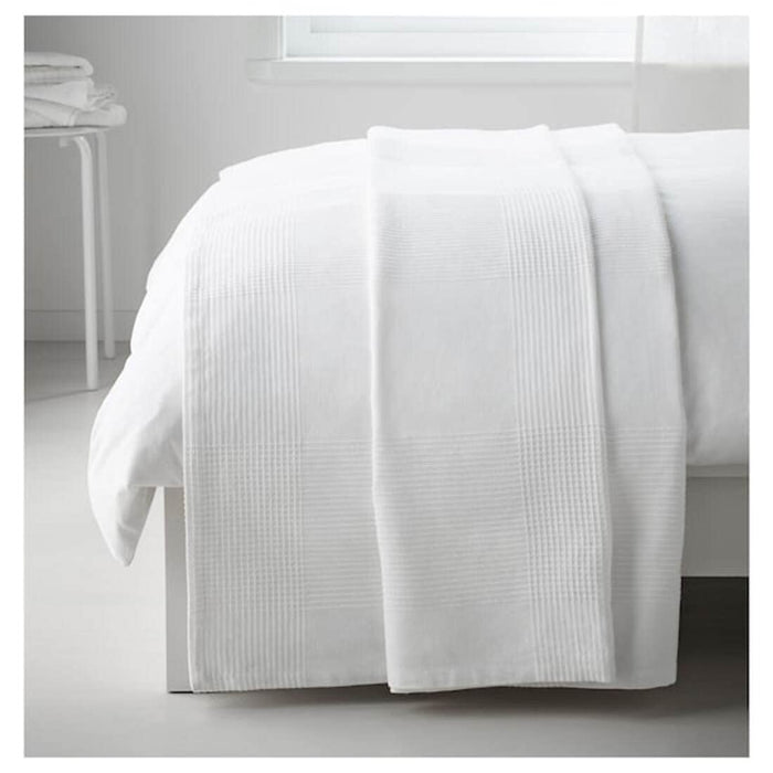 The white IKEA INDIRA Bedspread folded neatly on a shelf, showcasing its size (150x250 cm or 59x98 inches).