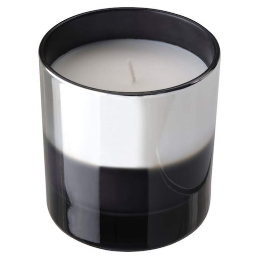 A glass jar with a lit IKEA scented candle, emitting a soft and warm glow.