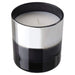 A glass jar with a lit IKEA scented candle, emitting a soft and warm glow.