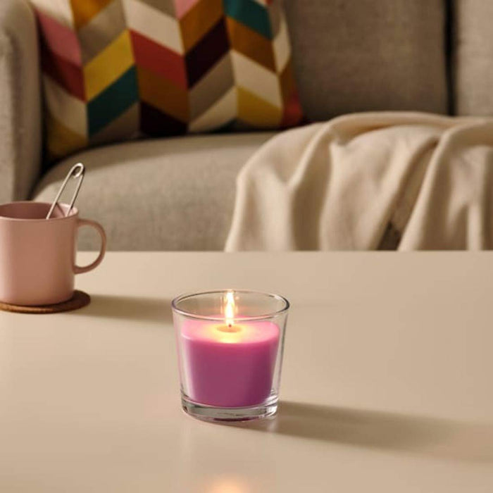A decorative glass candle holder with an IKEA scented candle, enhancing the ambiance of any living space with its warm and inviting glow.