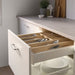 The bamboo utensil tray sitting on a kitchen counter, with wooden spoons, spatulas, and other utensils sticking out of the compartments.