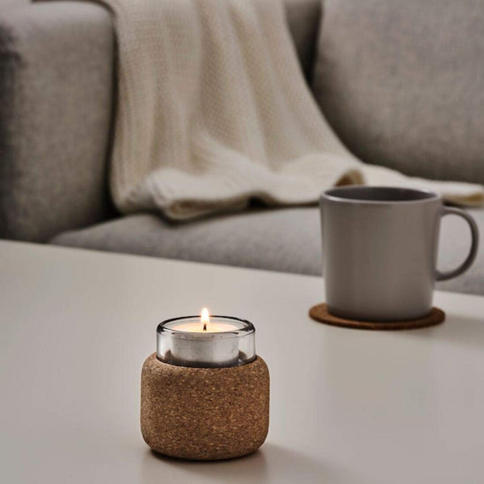 A white ceramic IKEA tealight holder with a pattern of small holes, lit with a small candle inside70454832