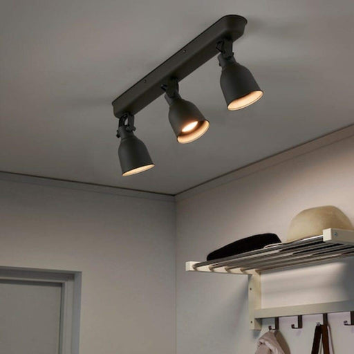 Three sleek and adjustable spotlights mounted on a black ceiling track from IKEA  90325636