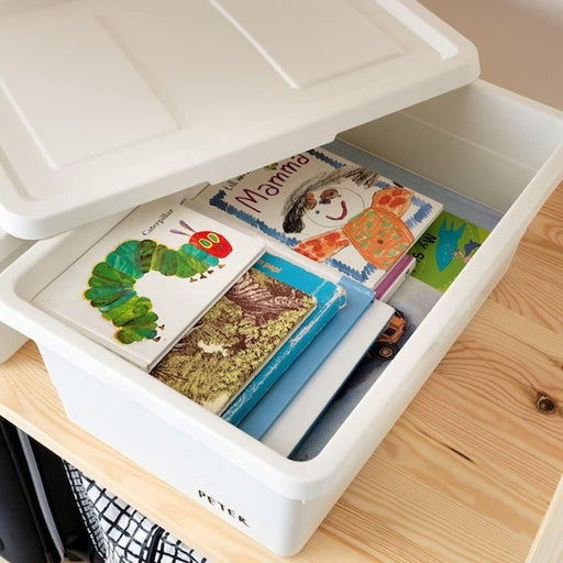 Open IKEA SOCKERBIT white storage box with children's books and toy truck on wooden floor