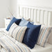 Multiple IKEA cushion covers in different colors and designs on a bed-60447427