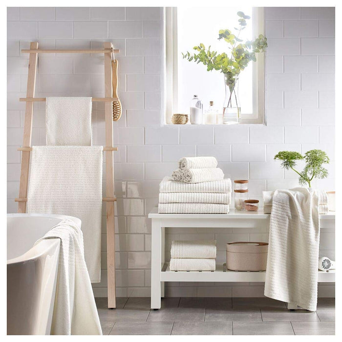 A white  hand towel from the Ikea 6 Piece Combo Set, hanging on a silver towel bar next to a white sink.