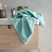 Turquoise IKEA hand towel lying on a wooden bathroom shelf, with a bar of soap and a plant nearby 30512872