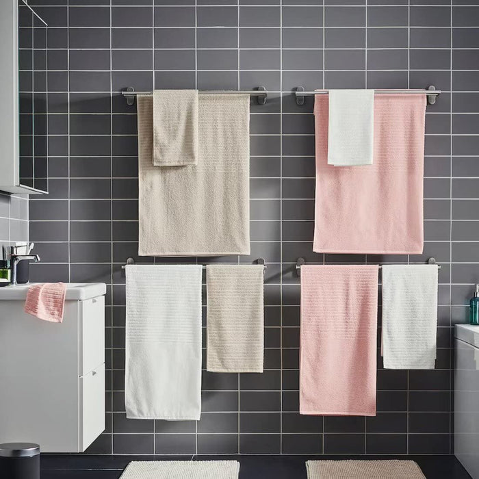 A pink hand towel from the Ikea 6 Piece Combo Set, hanging on a silver towel bar next to a white sink.