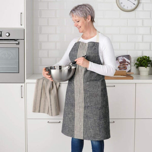 A female wearing a grey apron and holding a mixing bowl 70479578