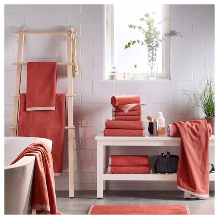 An overhead shot of an IKEA hand towel hanging from a towel rack, showcasing its convenient size and easy-to-hang design and folded and placed on a wooden table in a hall 50405159