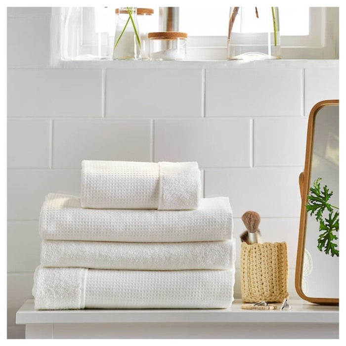 A folded Ikea hand towel in White color was placed on a wooden shelf.