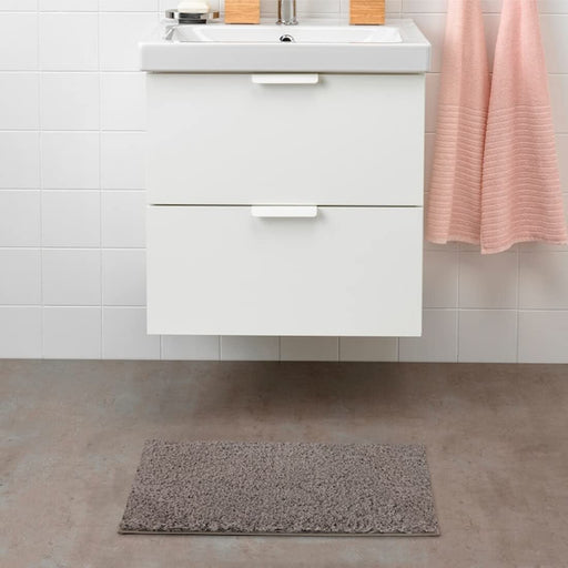 Beige IKEA bath mat placed on a bathroom floor, featuring a soft and absorbent texture and a non-slip bottom for secure footing 00489420