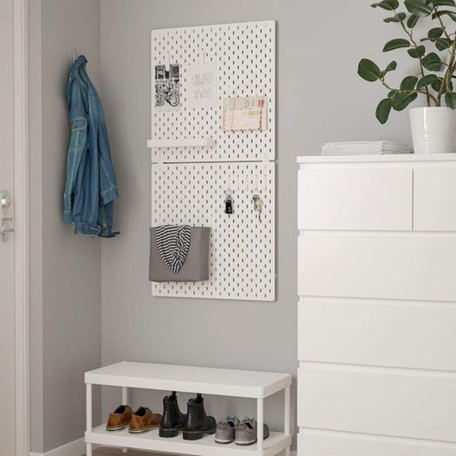 A white pegboard with colorful hooks and shelves attached to it. 30320806