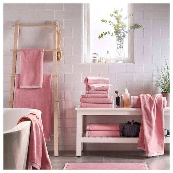 An overhead shot of an IKEA hand towel hanging from a towel rack, showcasing its convenient size and easy-to-hang design and folded and placed on a wooden table in a hall10405236