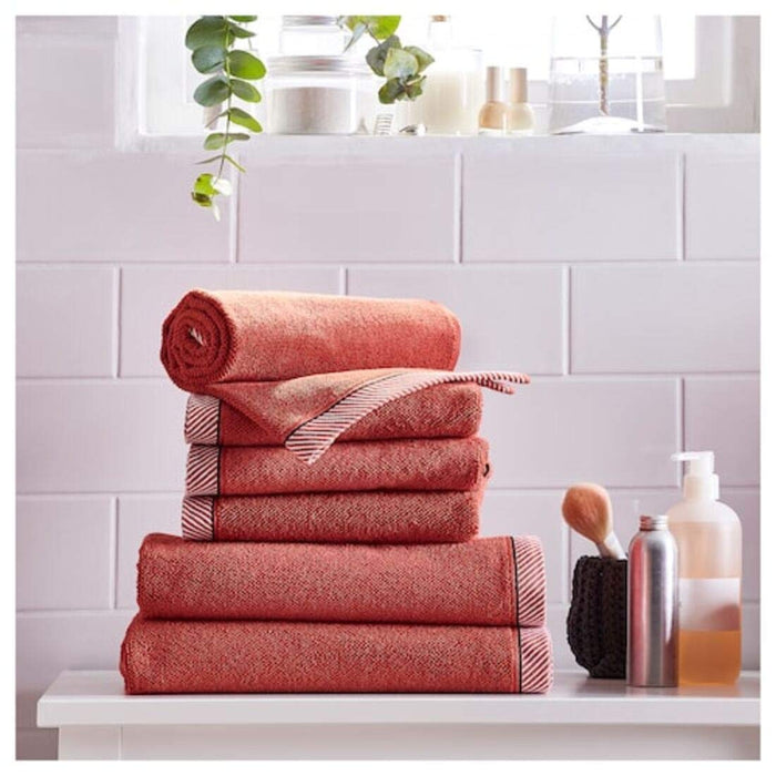 A red IKEA hand towel a It is folded neatly and placed on a wooden surface 50405159