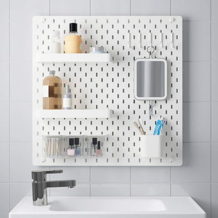 A white pegboard with a variety of accessories attached, including hooks and baskets. 39216594