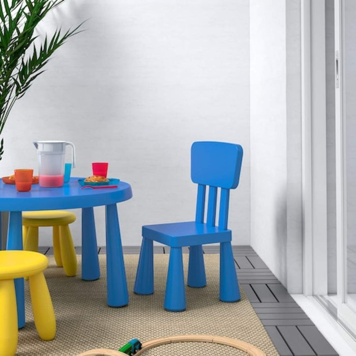 "A blue IKEA Children's Chair indoors, with a child drawing at a table"