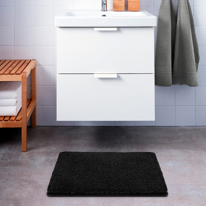 Dark grey IKEA bath mat placed on a bathroom floor, featuring a soft and absorbent texture and a non-slip bottom for secure footing 80489421
