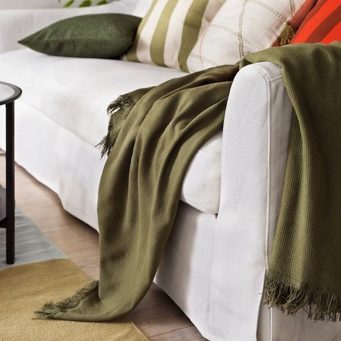 A soft, cream-colored fleece throw with a textured diamond pattern, folded neatly on a wooden bench.