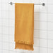 A hand reaching for a folded bath towel on a bathroom shelf.40502231