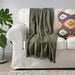 A plush, white faux-fur throw with a silky smooth underside, thrown over the back of a velvet armchair.