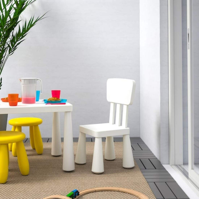 "A white IKEA Children's Chair in a classroom, with a child participating in a lesson