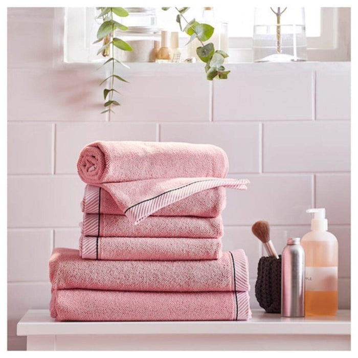 A pink IKEA hand towel a It is folded neatly and placed on a wooden surface 10405236