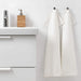 An image of a White hand towel hanging from a hook on a bathroom wall 00439430