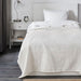 A close-up of the white IKEA INDIRA Bedspread, highlighting its textured weave and fringe details