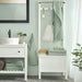A light green hand towel from the Ikea 6 Piece Combo Set, hanging on a silver towel bar next to a white sink.