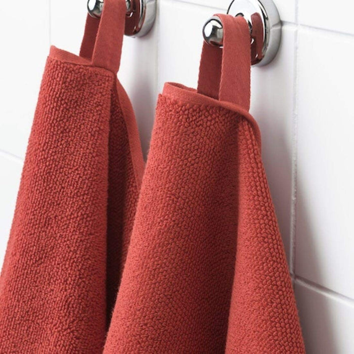 A close-up image of a simple and classic red hand towel hanging on a bathroom hook 50405159