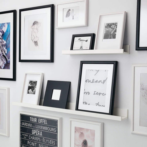 An image of the IKEA Picture Ledge shelf mounted on a white wall with various framed photos displayed on it.  30297467